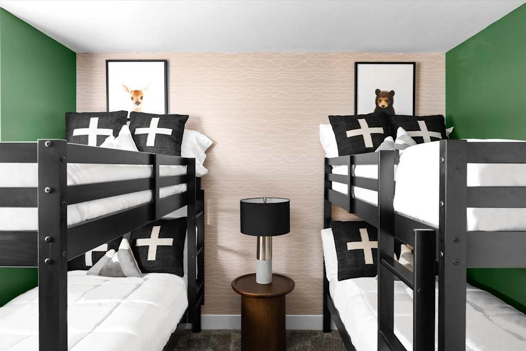 The Evergreen — bunk room featuring two sets of dark wood bunk beds flanking a bedside lamp
