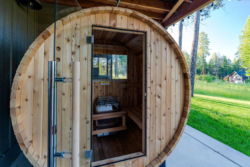 The Evergreen — wooden outdoor barrel sauna with open door on a concrete patio
