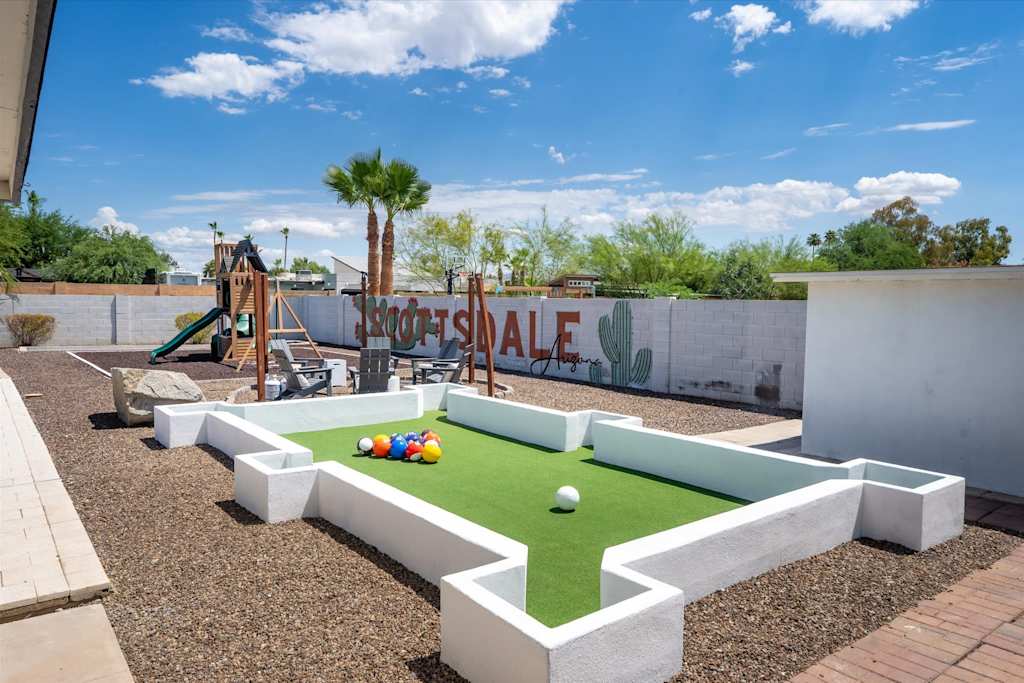 The Scottsdale Social — outdoor footpool game area on gravel next to a play structure and perimeter wall