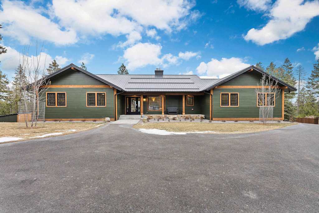 The Tamarack — exterior view of a green lodge with wood trim and a paved driveway