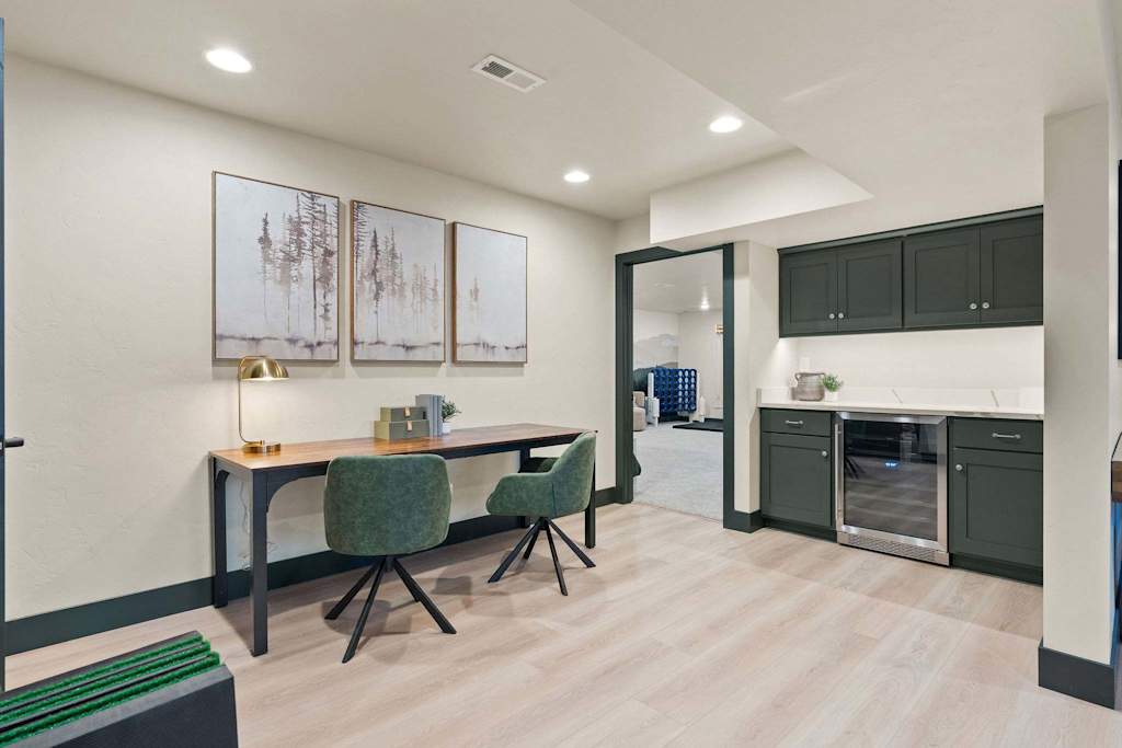 The Tamarack — sitting area with a wooden desk, green chairs, and a mini bar counter