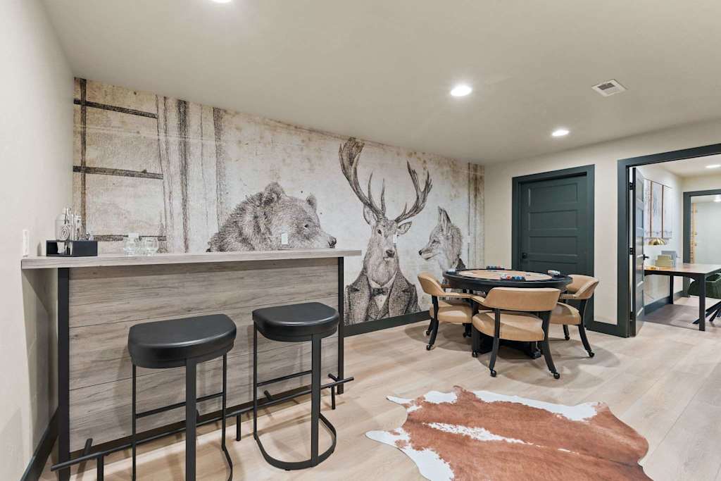 The Tamarack — bar counter with stools and a round poker table in front of a wildlife wall mural
