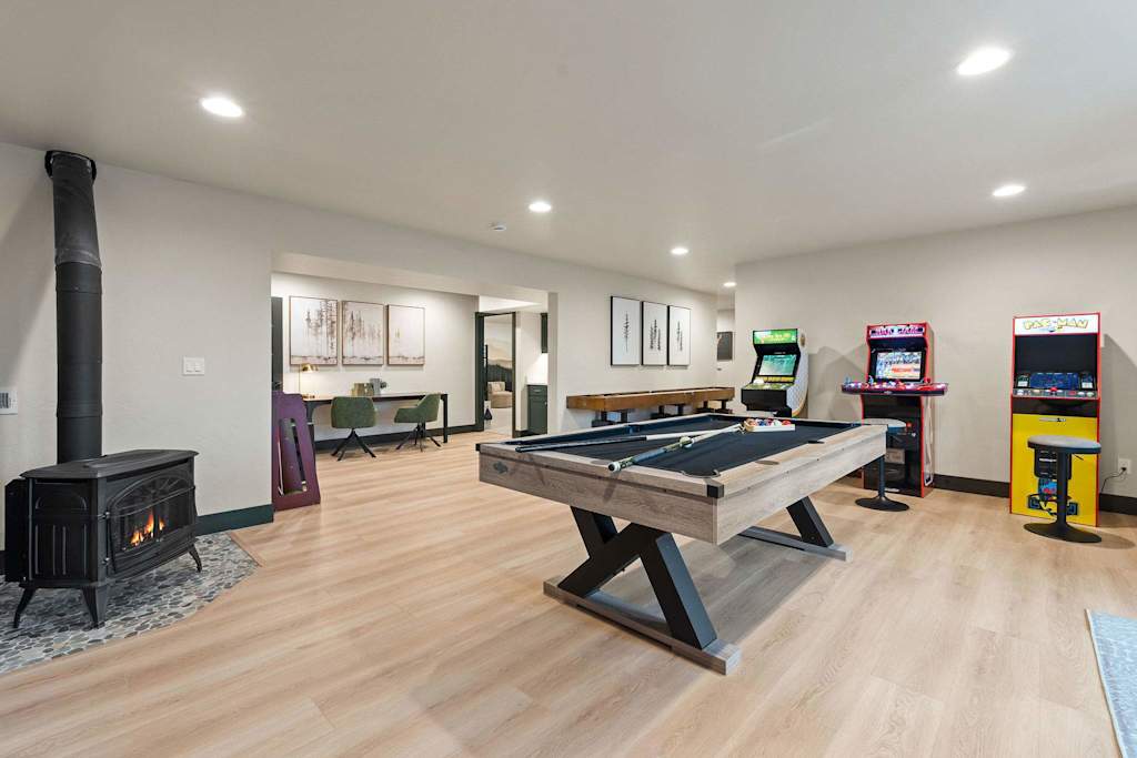The Tamarack — spacious game room with a pool table, wood stove fireplace, and classic arcade machines