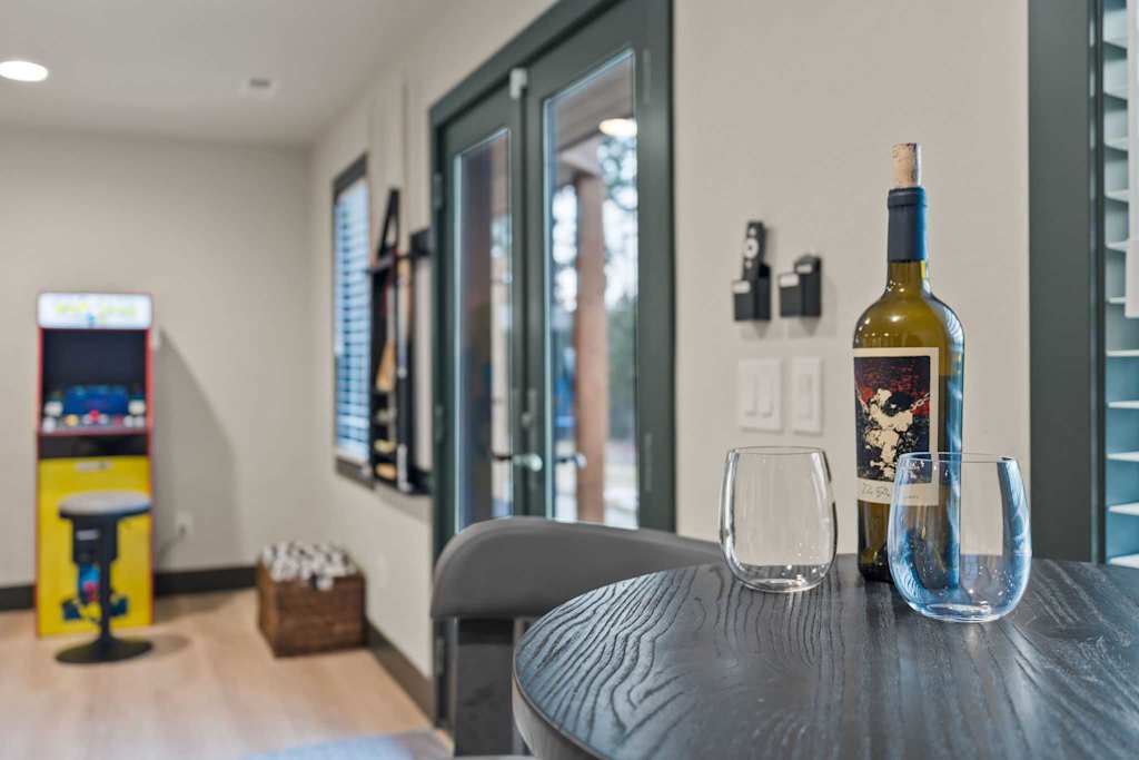 The Tamarack — wine bottle and two empty glasses on a table with an arcade game in the background