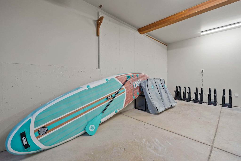 The Tamarack — stand-up paddleboard leaning against a wall next to gear bags and boot dryers