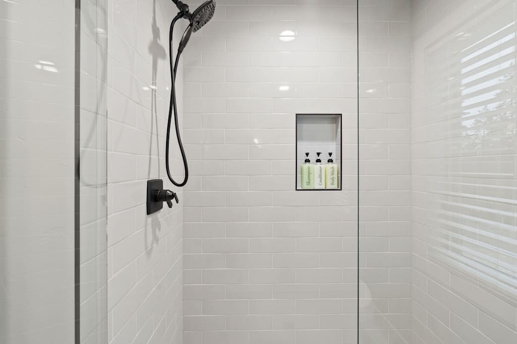 The Tamarack — walk-in shower with white subway tile, black fixtures, and a recessed toiletry niche