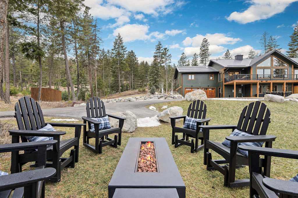 The Tamarack — outdoor seating area with black adirondack chairs surrounding a rectangular fire pit table overlooking the lodge