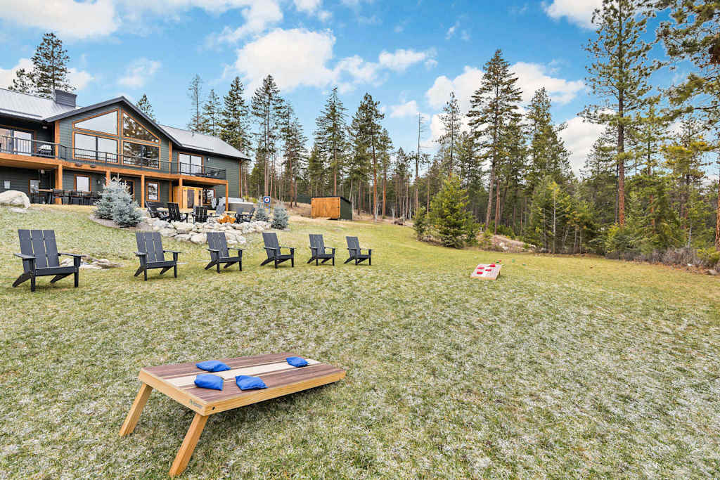 The Tamarack — lawn game cornhole set in the grass with chairs and lodge exterior in the background