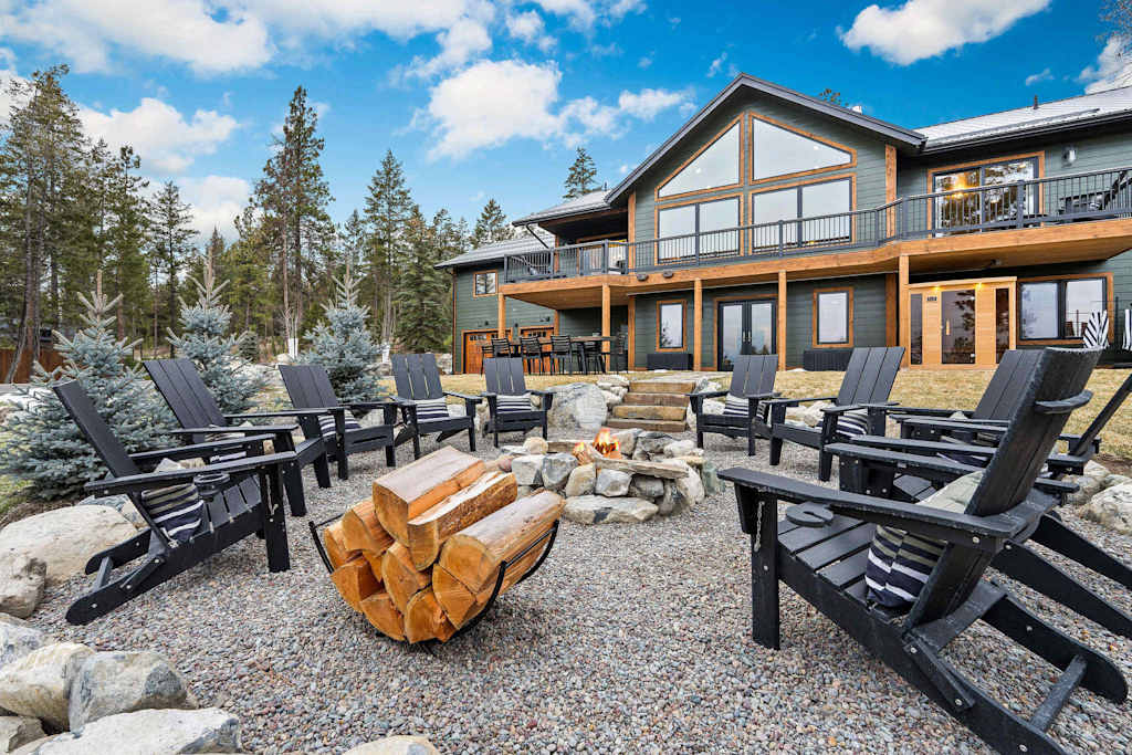 The Tamarack — gravel fire pit area with adirondack chairs and log rack in front of the lodge