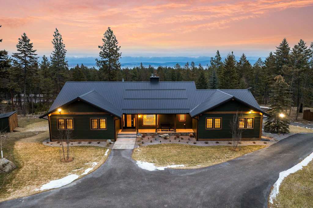 The Tamarack — exterior front view of dark green lodge with paved driveway at dusk