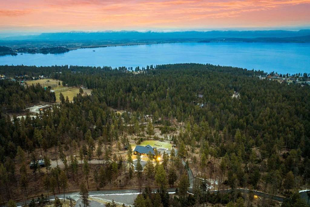 The Tamarack — aerial view of lodge surrounded by pine forest with large lake in background