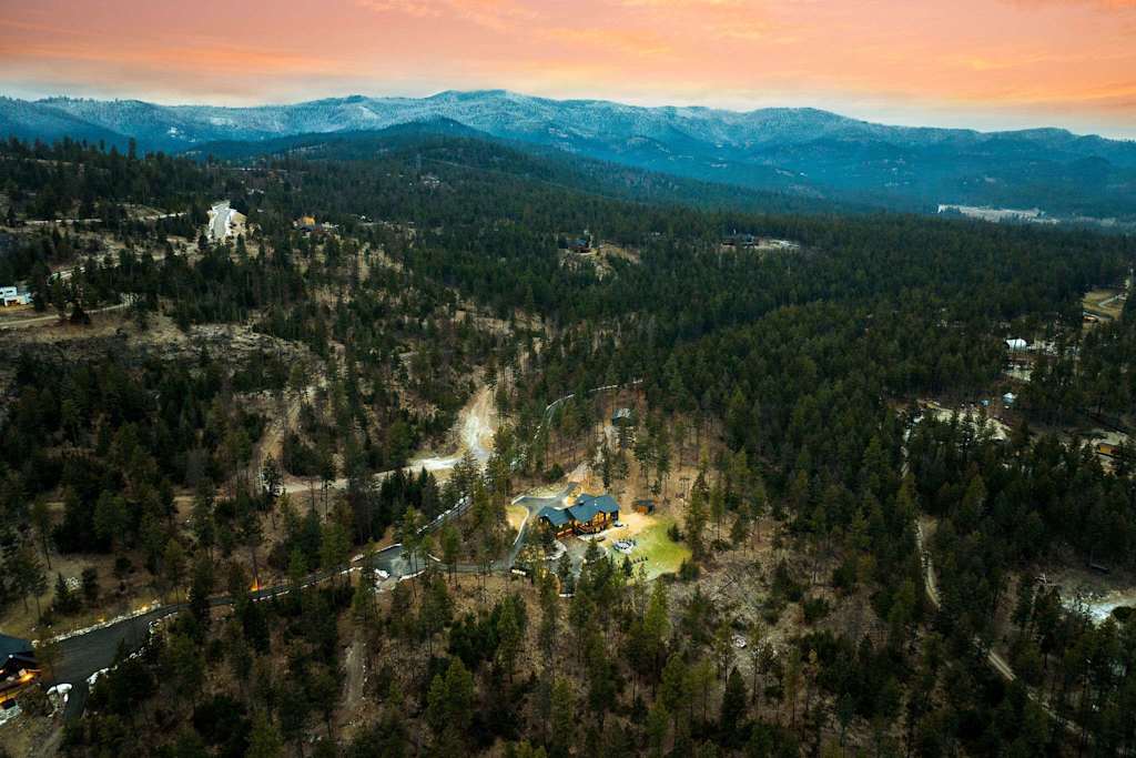The Tamarack — aerial wide view of lodge in forest with snow-dusted mountains in distance