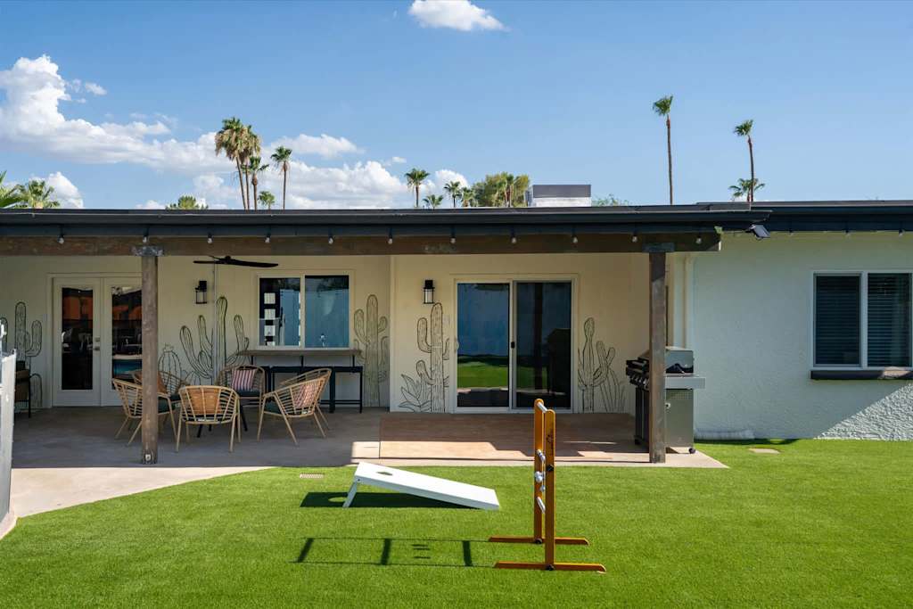 The Sunkiss — backyard covered patio with outdoor seating, lawn games on artificial turf, and gas grill