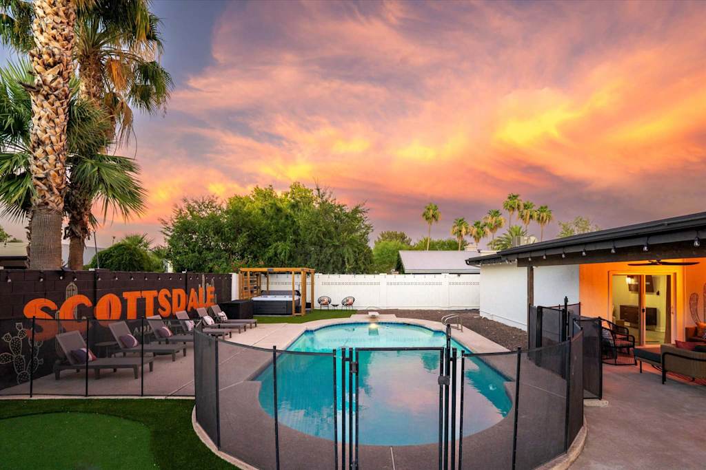 The Sunkiss — backyard with a fenced swimming pool, hot tub, lounge chairs, and a sunset sky