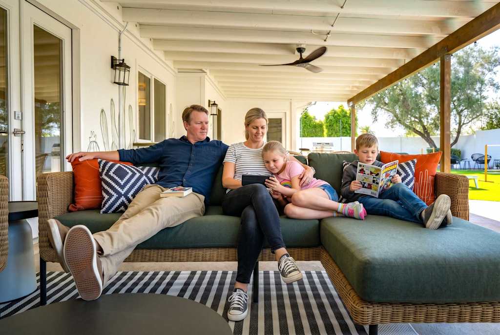 The Sunkiss — family sitting together on a covered patio sectional sofa outdoors