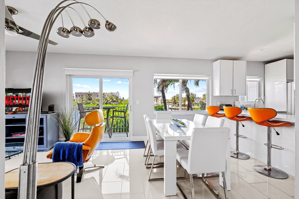 Pompano Condo: The open living area has a dining table, a kitchen bar and balcony doors