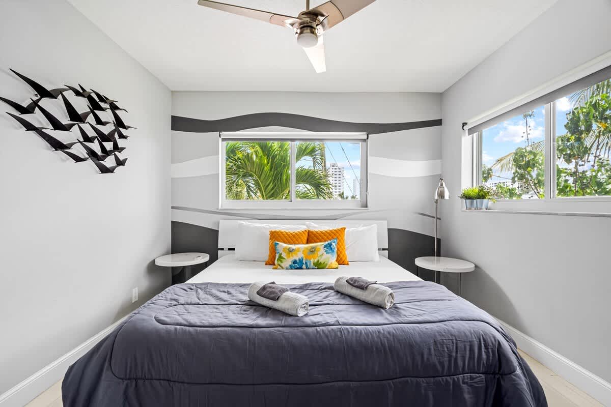 Pompano Condo: This bedroom has a bed and two windows with palm tree views