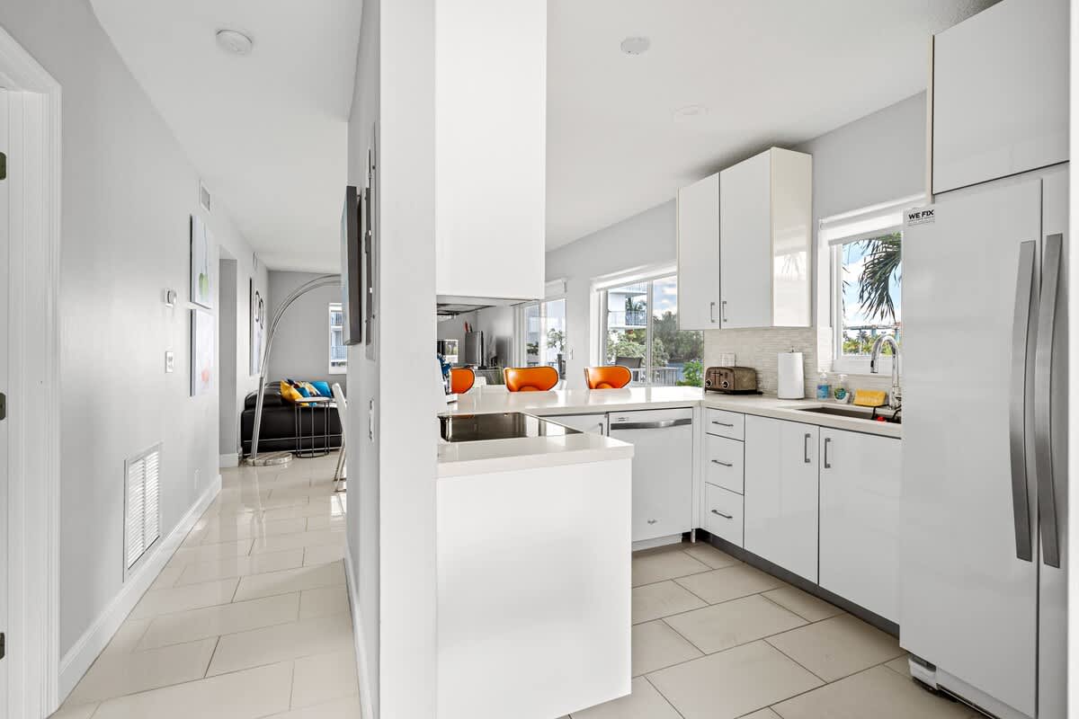 Pompano Condo: The kitchen has white cabinets, a dishwasher and a full-size fridge
