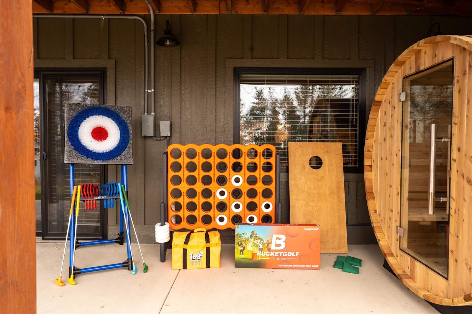Covered patio with outdoor games and a wooden barrel sauna