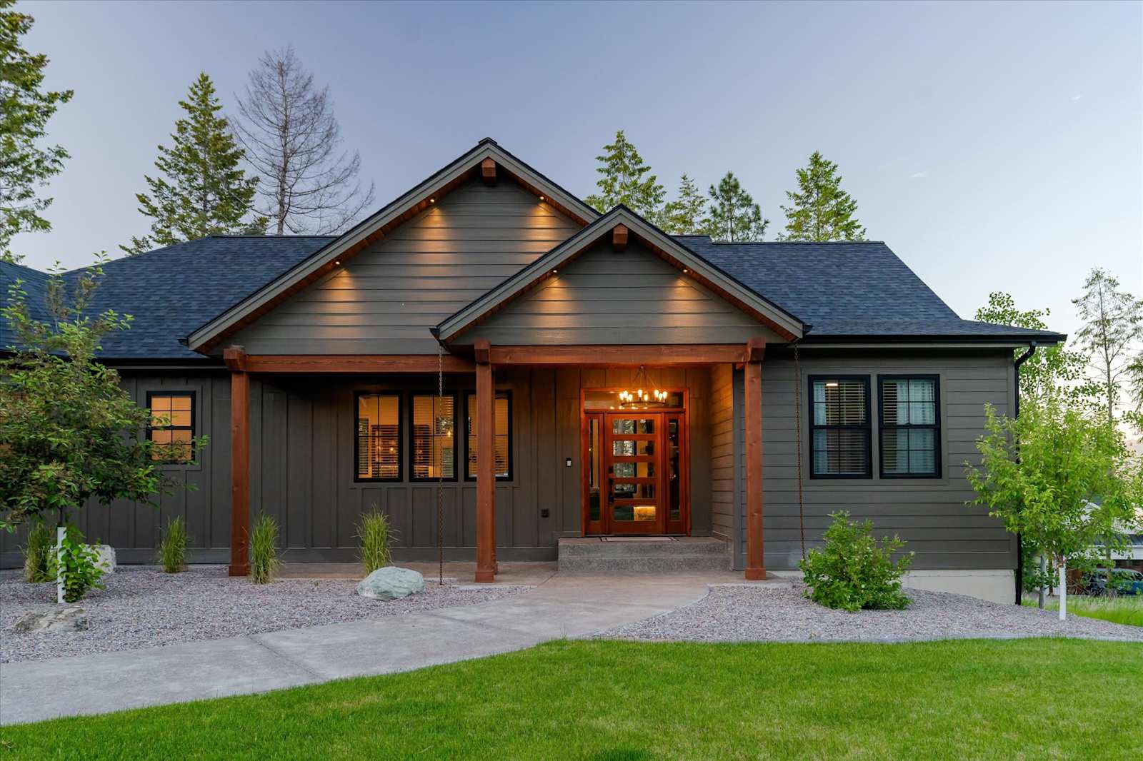 Front of The Evergreen with covered entry, lawn and pine trees at dusk