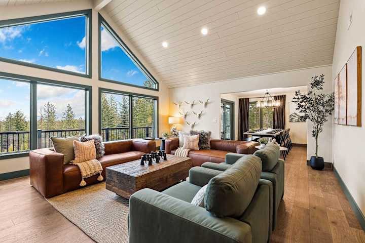 Vaulted great room with fireplace, leather seating and tall windows