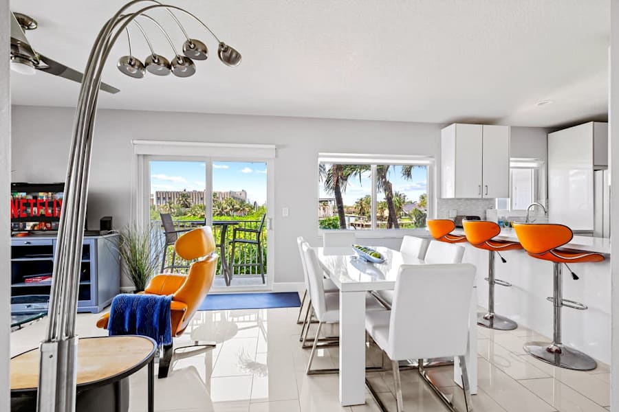 Pompano Condo: The open living area has a dining table, a kitchen bar and balcony doors