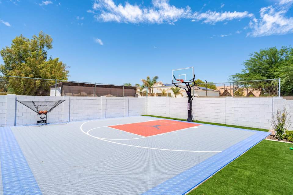 Blue and red basketball court beside the backyard lawn