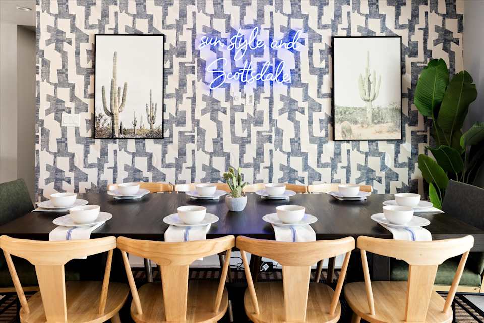 Long dining table set beneath linear pendant lights