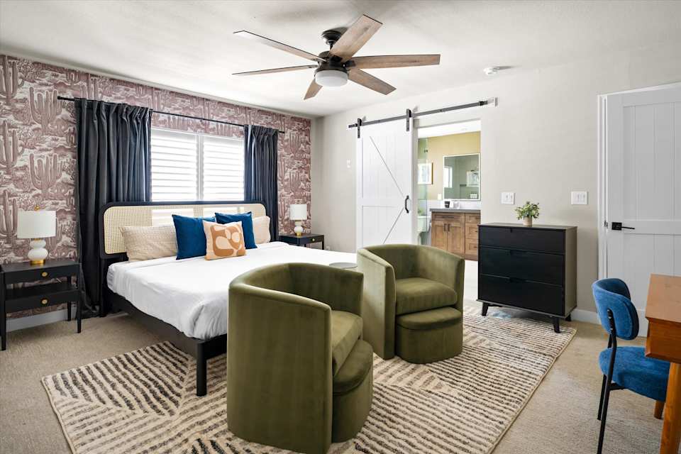 Bedroom with upholstered bed and green lounge chairs