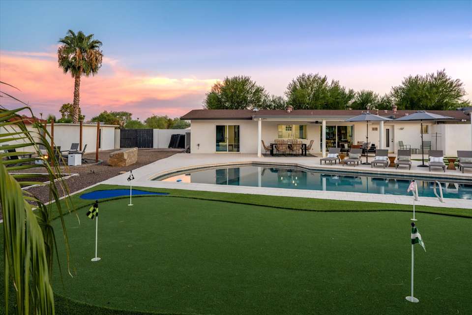 Wide daytime view of the pool, lawn and backyard amenities