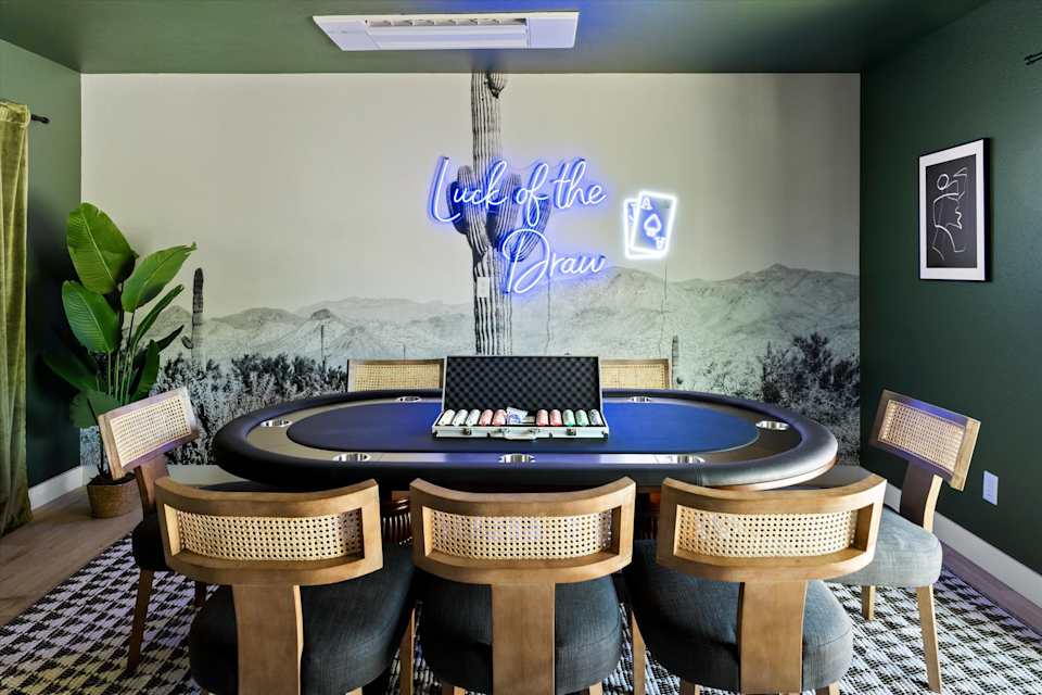 Round game table and chairs beneath a neon wall sign