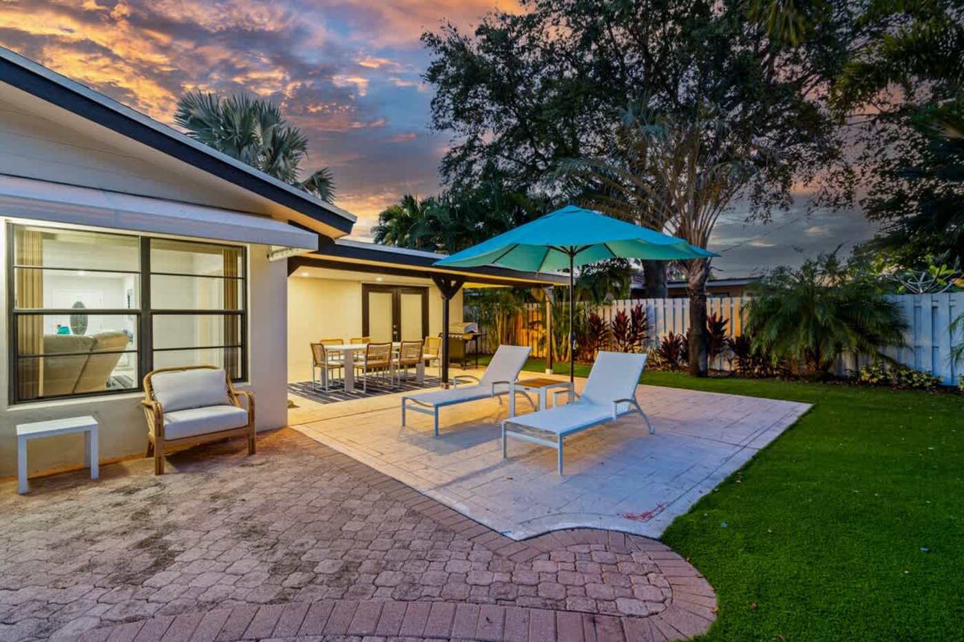 Gardens By The Sea: Covered patio and lawn at sunset, with loungers on the deck