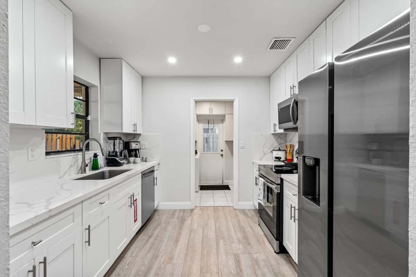 Gardens By The Sea: Kitchen with dishwasher and sink, utility room beyond