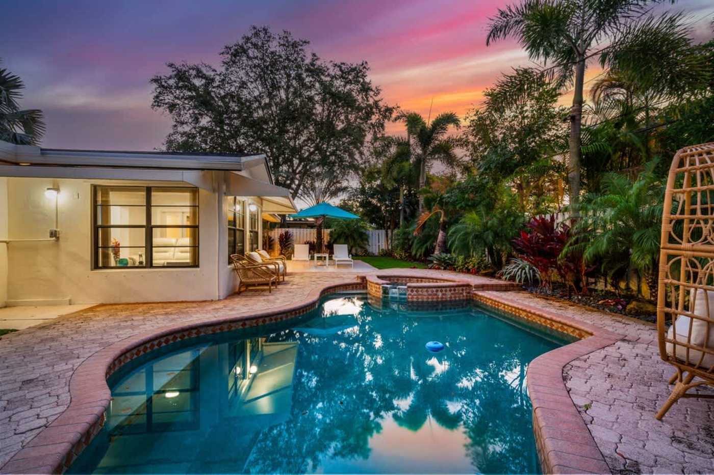 Gardens By The Sea: The house lit at dusk, with the pool in the foreground