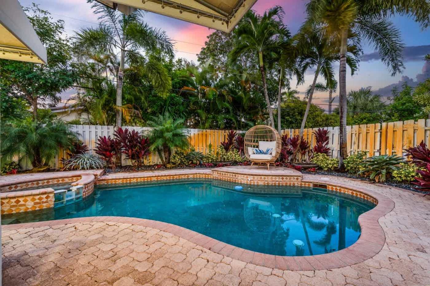 Gardens By The Sea: Pool and paver deck at dusk, with the garden lit behind