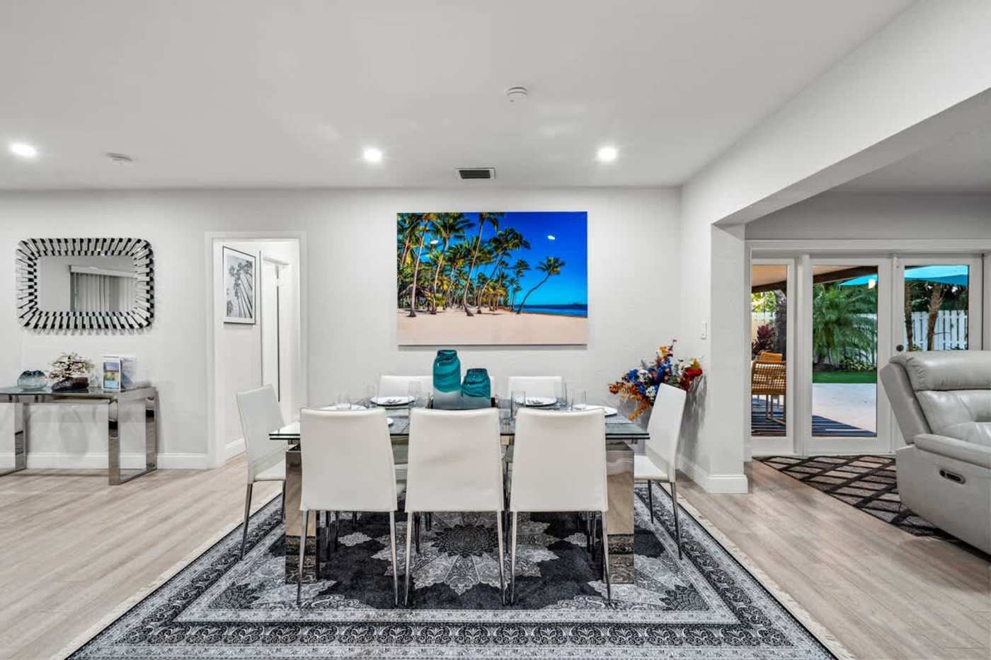 Gardens By The Sea: Dining table for six under artwork, with the patio doors beyond