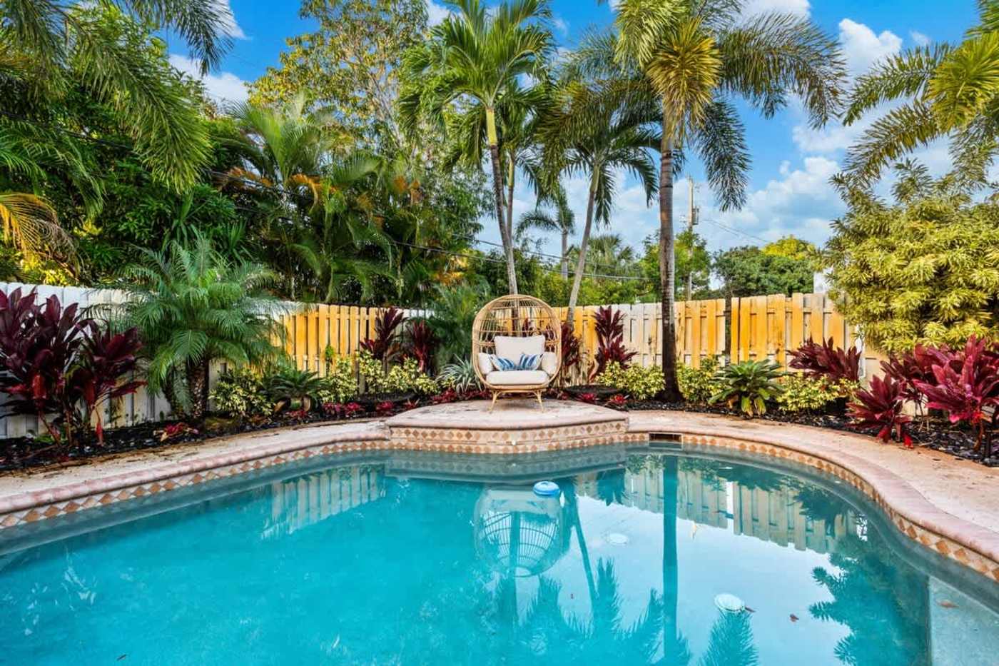 Gardens By The Sea: Pool with hanging egg chair, palms and planting behind