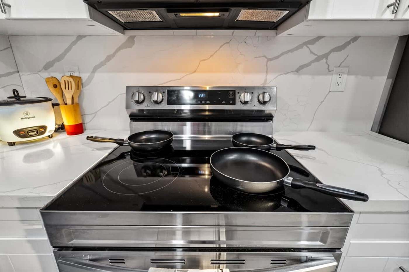 Gardens By The Sea: Electric hob and range hood, with pans on the counter