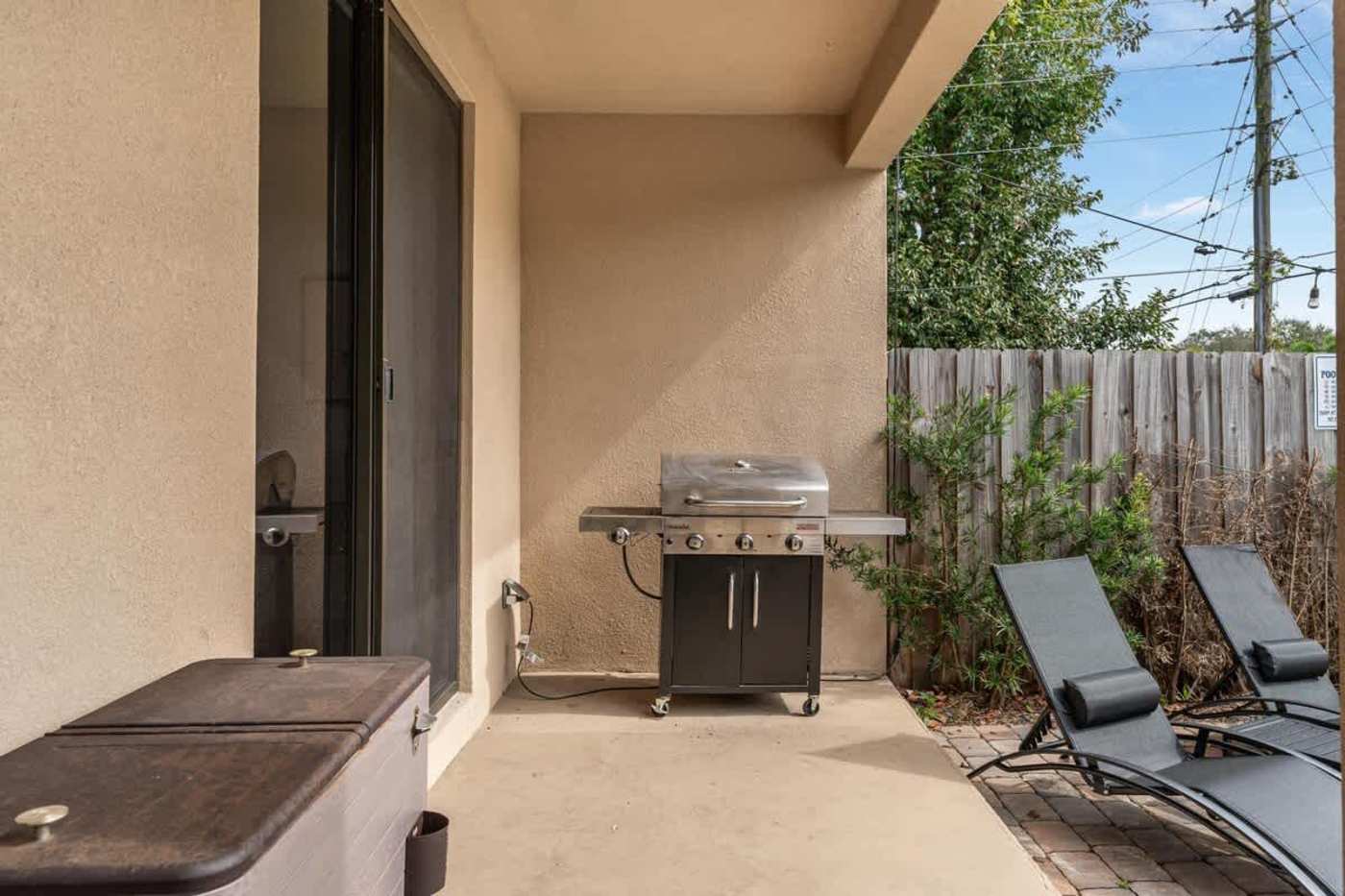 The Arcade House: Gas grill and storage on the covered patio, beside the loungers