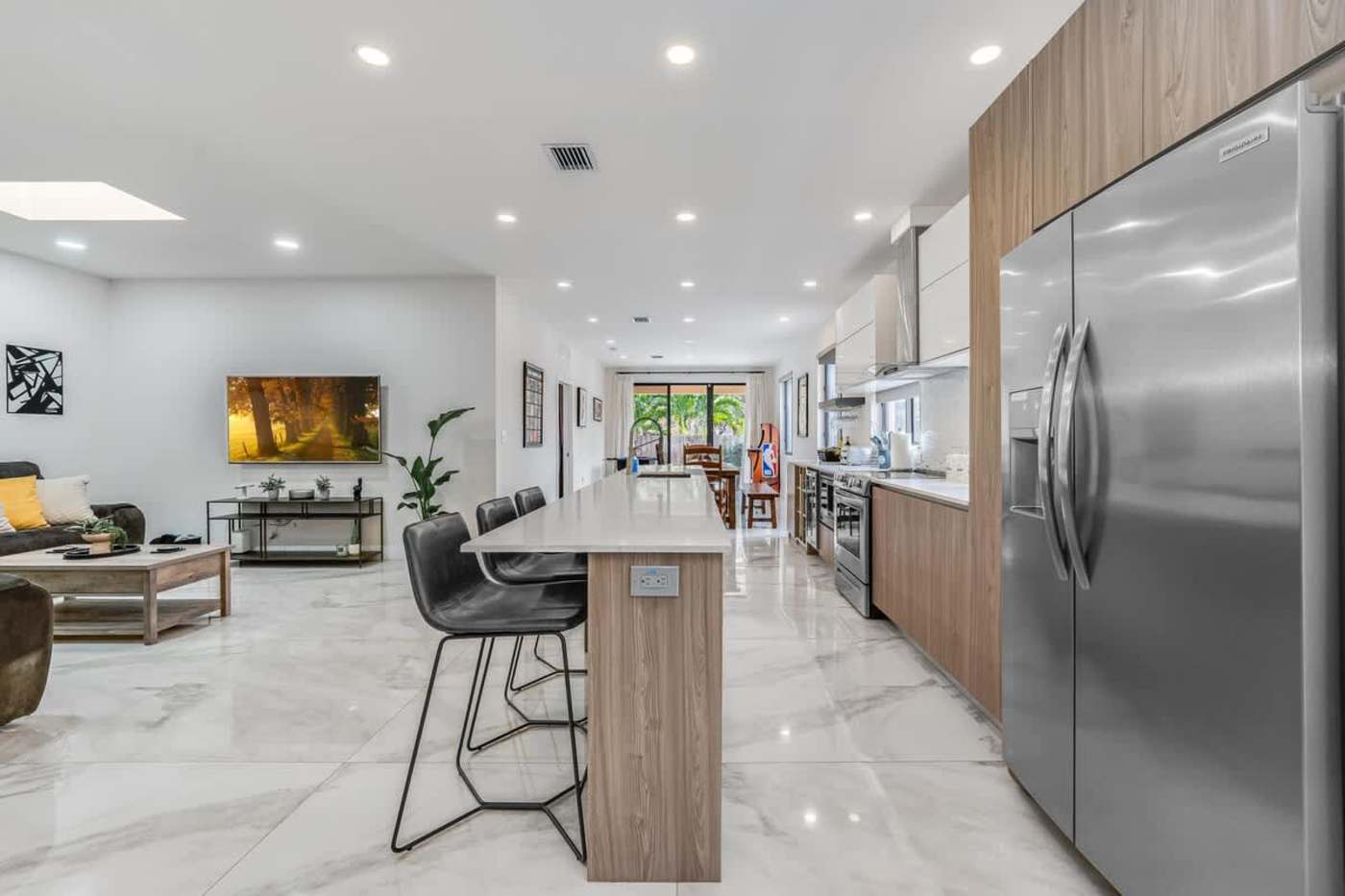 The Arcade House: Kitchen island with bar seating, looking through to the living room