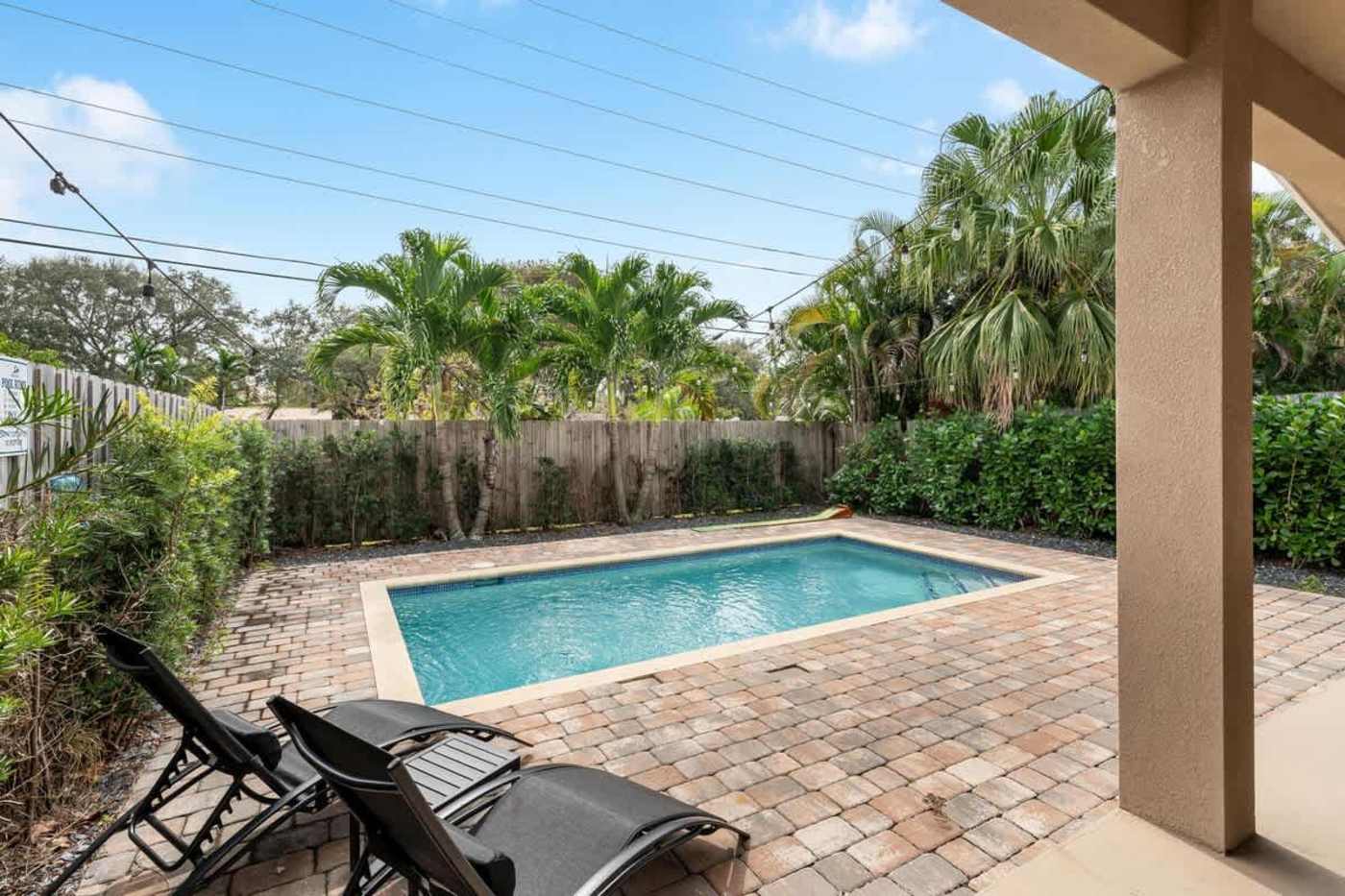 The Arcade House: Heated pool and paved deck, with loungers and palms behind