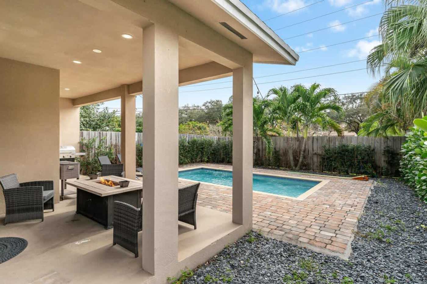 The Arcade House: Covered patio with fire pit seating, looking out to the pool