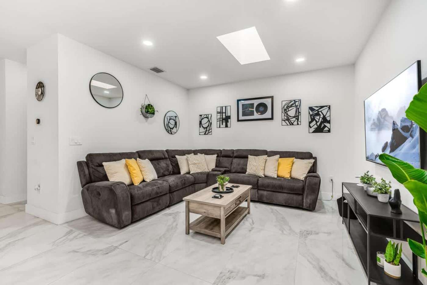 The Arcade House: Living room with a large sectional, smart TV and skylight