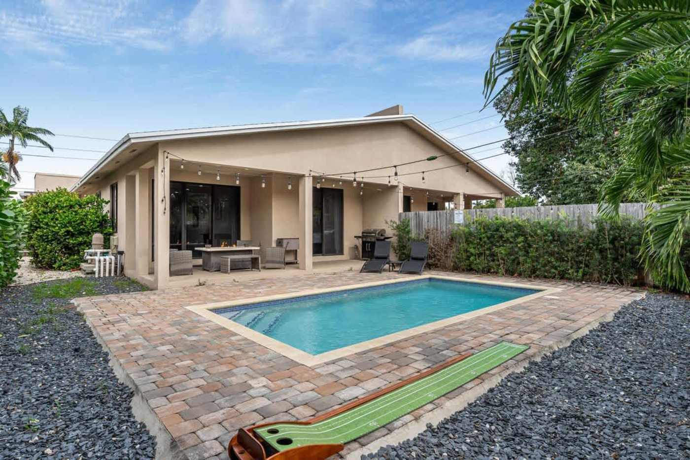 The Arcade House: Pool and paved deck with a putting mat on the gravel