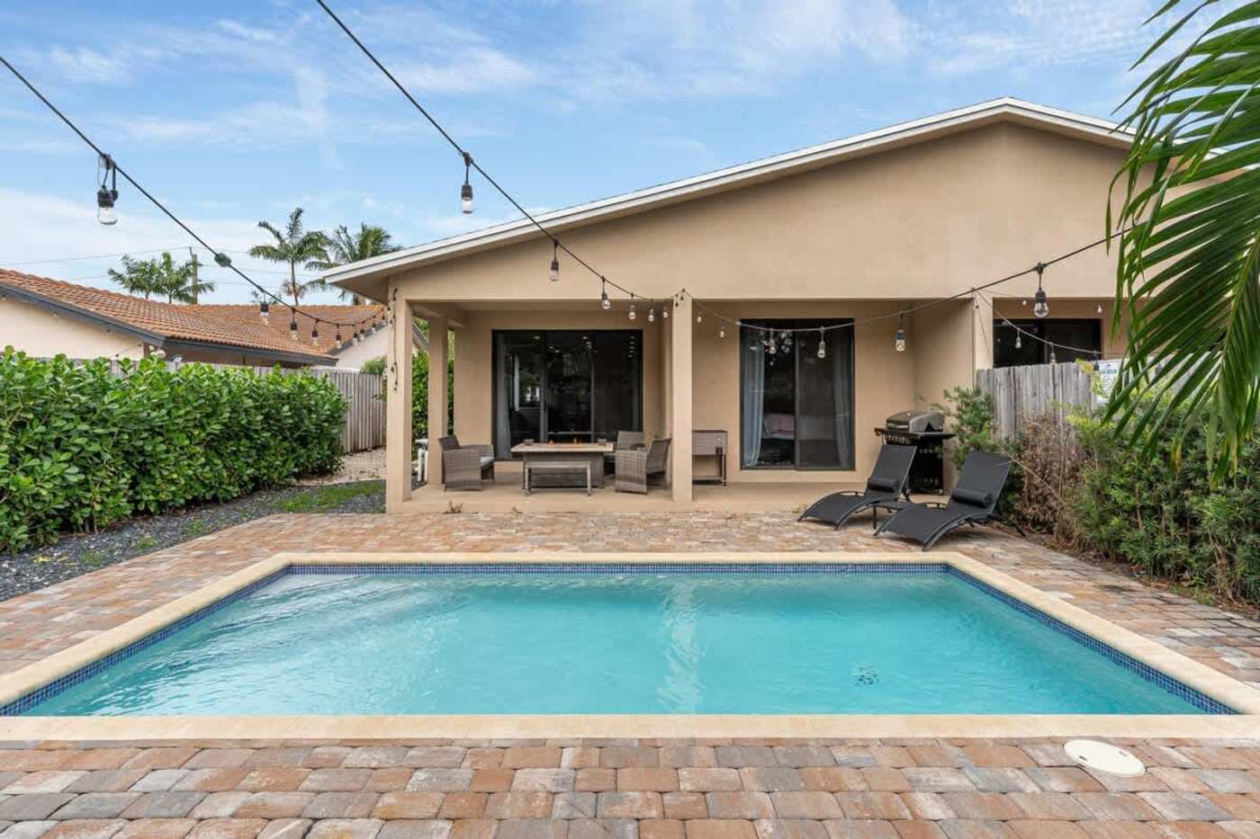 The Arcade House: Heated pool and deck, with the covered patio and string lights behind