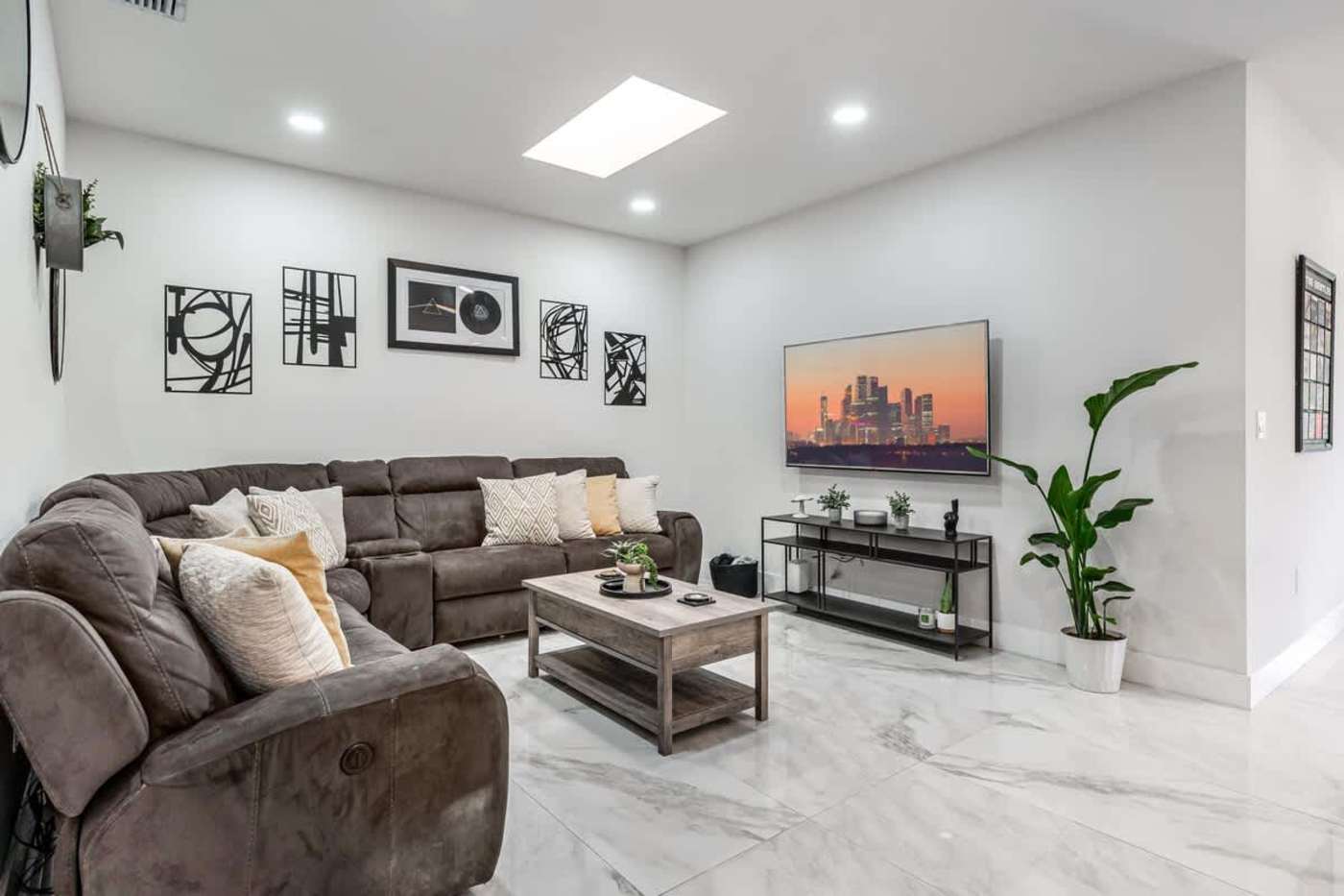 The Arcade House: Living room with sectional sofa, smart TV and a skylight
