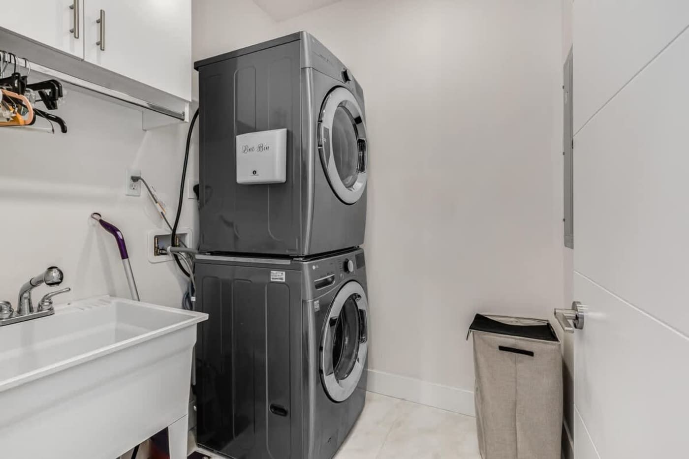 The Arcade House: Utility room with stacked washer and dryer and a deep sink