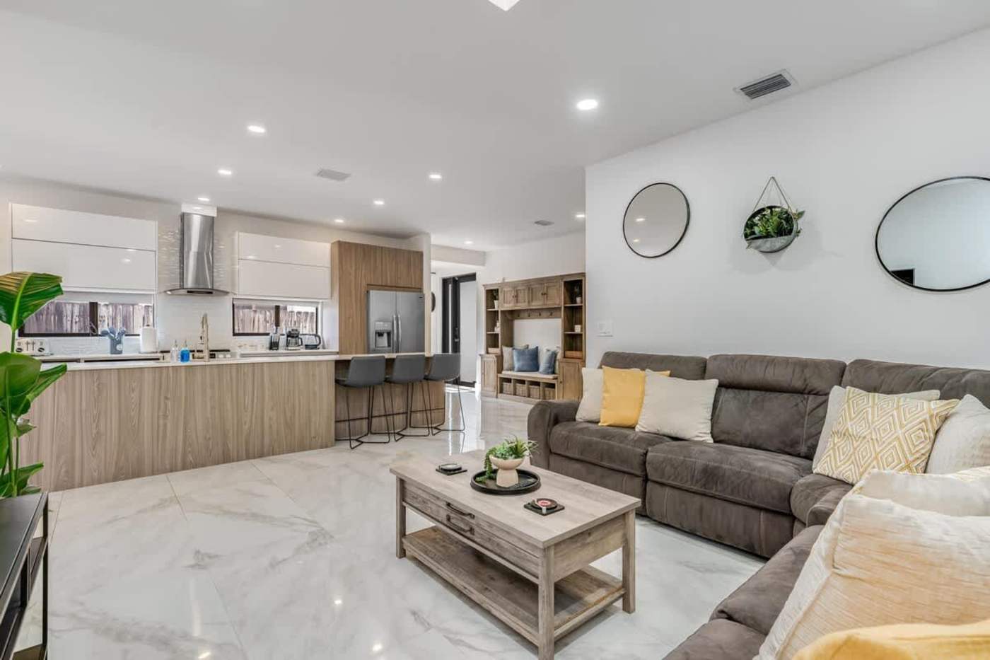 The Arcade House: Open plan living and kitchen, with sectional seating and island stools