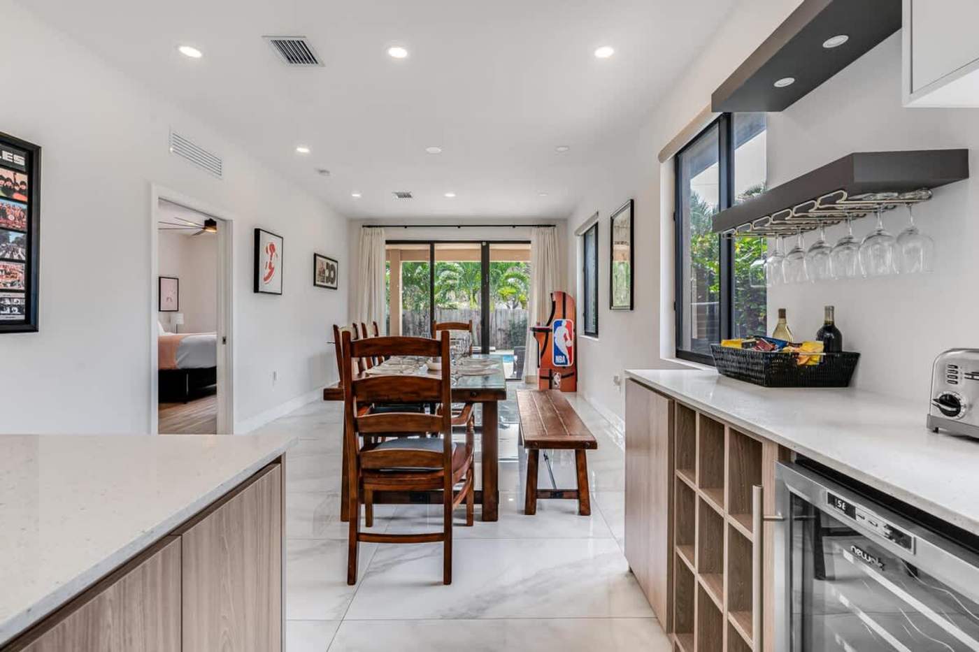 The Arcade House: Dining table and kitchen, with the pool through the doors