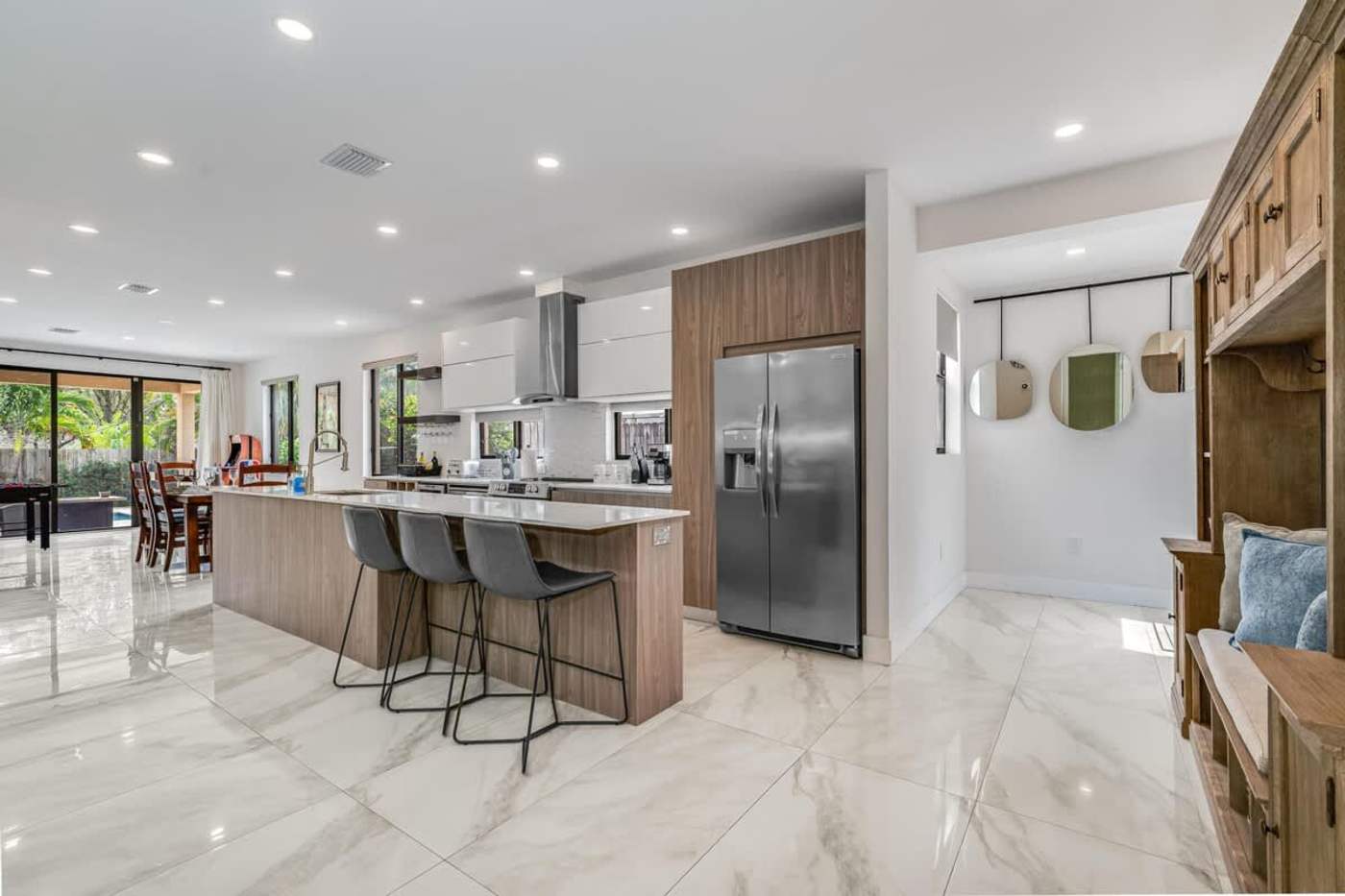 The Arcade House: Kitchen with island seating for three, range hood and large fridge